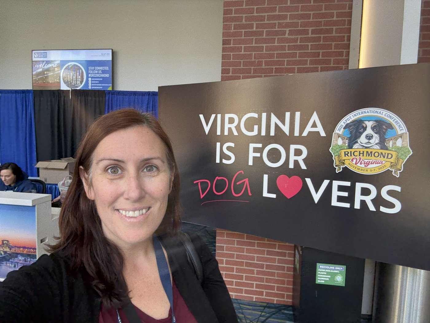 Courtney beside the Virginia is for Dog Lovers sign at the APDT conference